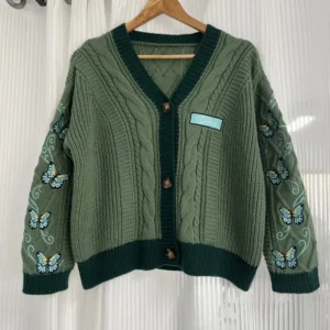 Cozy green knit sweater with butterfly motifs and dark green trim
